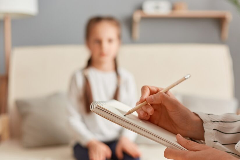 Child speaking with a psychologist who is making notes in a pad