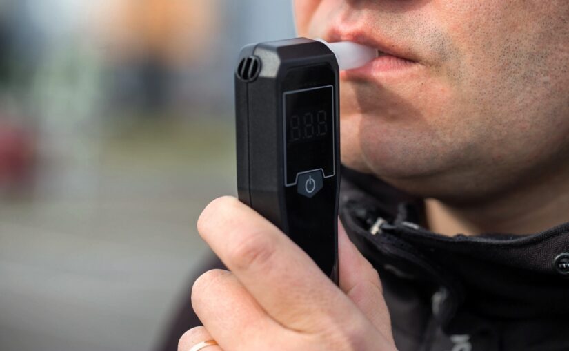 Man performing field sobriety test with breathalyzer